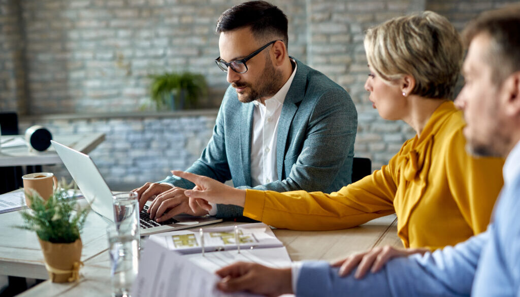 Real estate agent using laptop while having a meeting with a cou