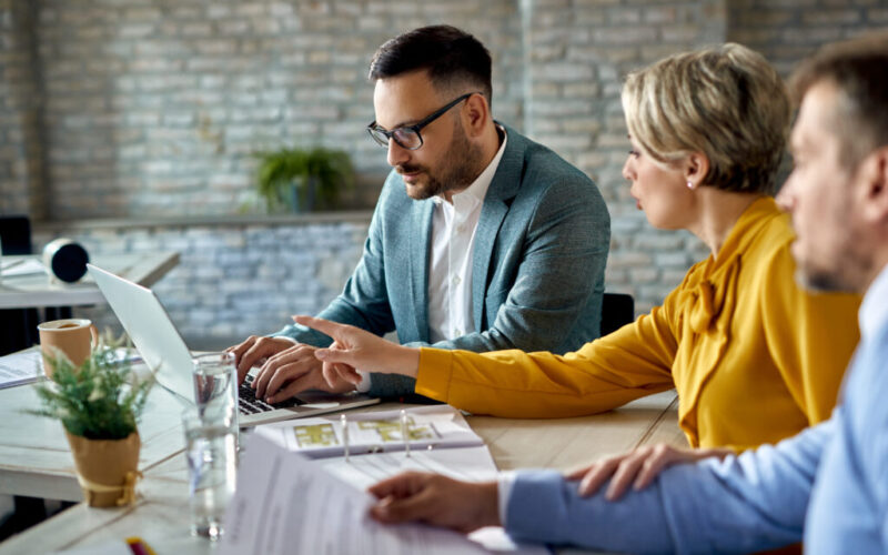 Real estate agent using laptop while having a meeting with a cou Real estate agent using laptop while having a meeting with a cou